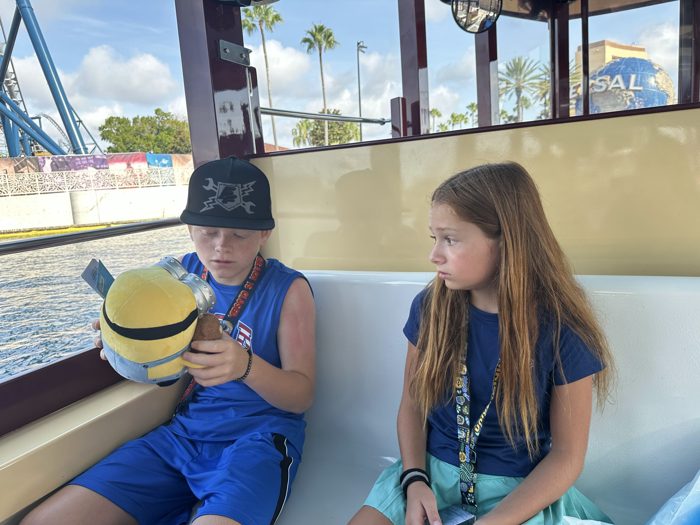 The kids share a bench on the water taxi, Minion plush in hand as the Universal globe glides past across the lagoon.