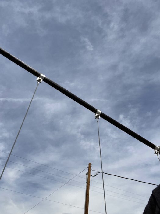 The bridge's steel cables and tower arm stretching up into the open blue sky.
