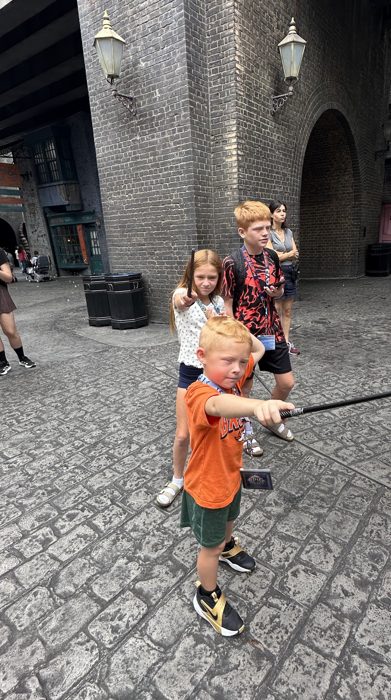 Wands drawn and aimed, the kids strike a dramatic pose under the archway.