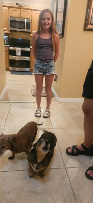 One of the kids poses in the kitchen while the family's two dachshunds circle underfoot.