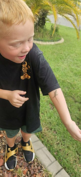 One of the kids watches, delighted, as the lizard makes its way up his arm.