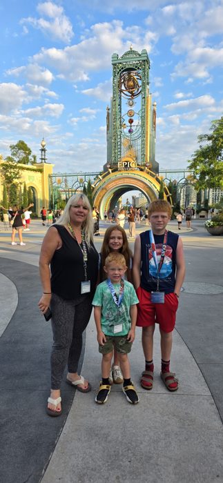 The family poses together beneath the towering astronomical clock gate at the entrance to Epic Universe.