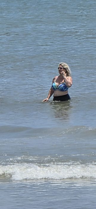 Standing waist-deep, watching the waves roll in.