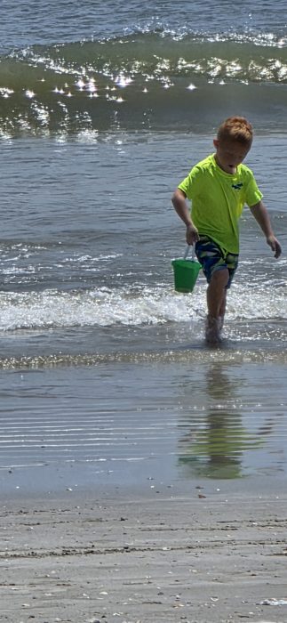 Wading back out through the wash with the green bucket for another round of beach treasure hunting.