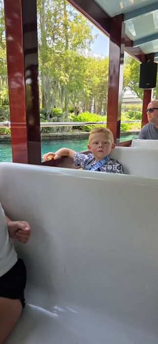 One of the kids watches the scenery drift by from the water taxi, dad seated in the row behind.