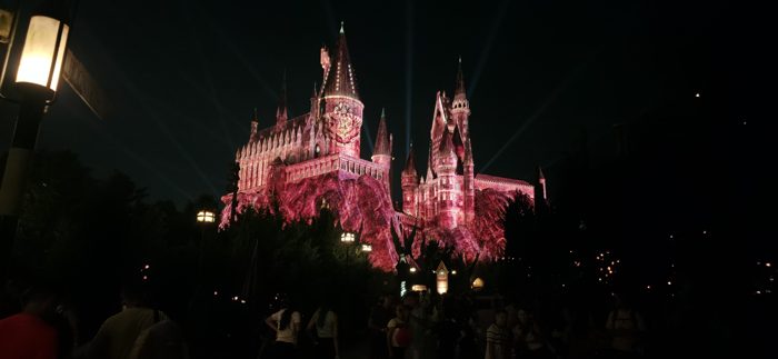 Beams of light sweep across the sky as the castle's projection show shifts through red.