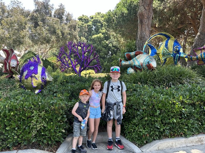 The kids strike a pose in front of the giant flowering dinosaur topiaries in the garden.