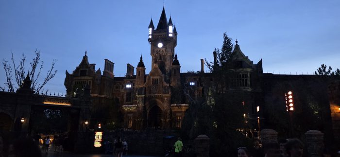 The towering Frankenstein castle facade glows against the evening sky as dusk settles over the park.