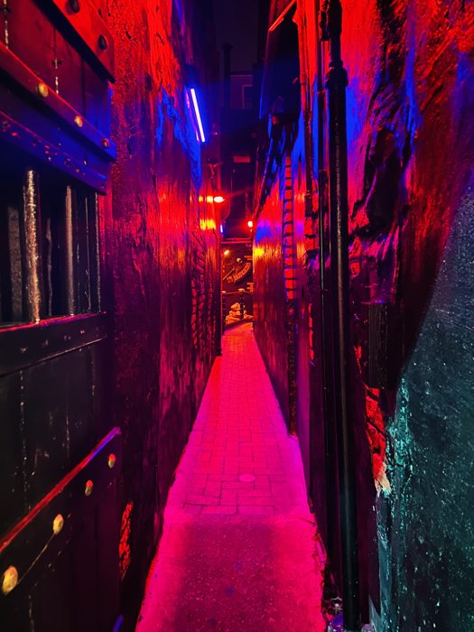 Red-and-purple lights wash the narrow alley leading into The Dungeon.