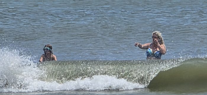 Catching a wave together as it breaks behind them.