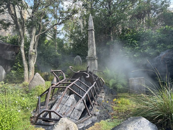 Fog rolls through the graveyard, swirling around the wrecked cart and headstones.