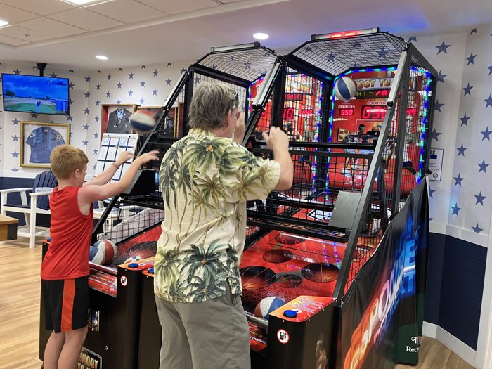 A friend and one of the kids go head-to-head at the basketball arcade machine.