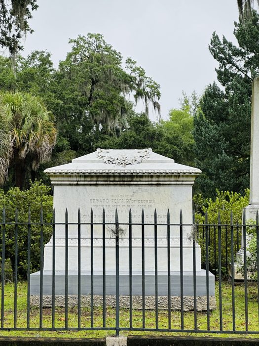 A grand stone tomb stands behind its wrought-iron fence beneath the cemetery oaks at Bonaventure.