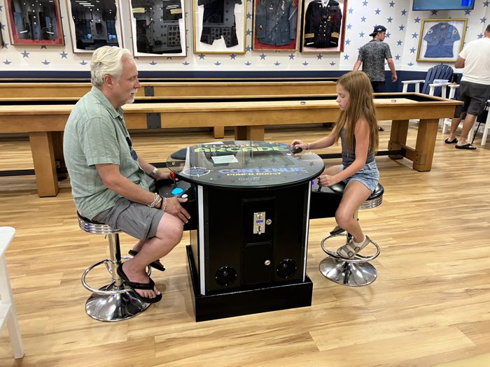 A quiet head-to-head at the arcade table with the shuffleboard lanes stretched out behind them.