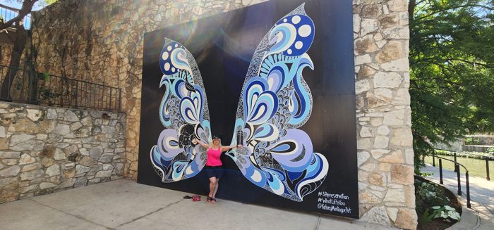 Admiring the sweeping blue butterfly mural tucked against the old stone wall.