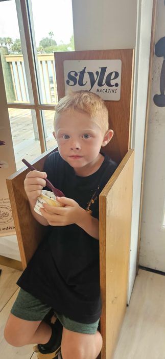 One of the kids digs into a cup of ice cream while perched in a giant magazine-cover photo op.