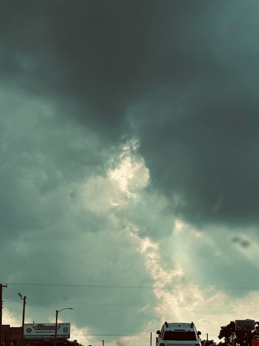 A dramatic storm cell building dark and green over the highway.