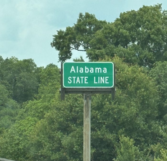 Officially in Alabama at last, marked by the green 'Alabama State Line' sign along the highway.