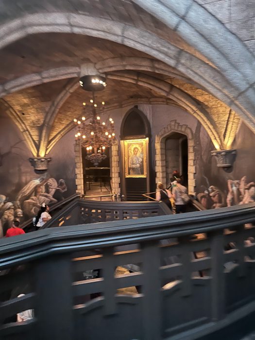Sweeping stone stairs and a candlelit chandelier set the gothic mood inside the queue.