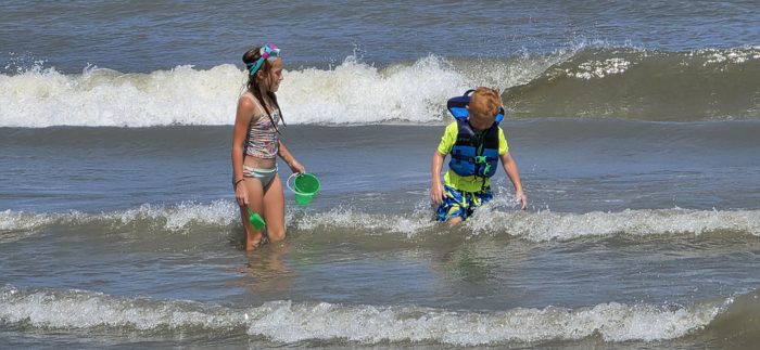 The kids wade side by side through the waves, sand buckets swinging and snorkel gear at the ready.