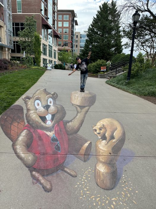 Posing with the playful 3D chalk-art chipmunks on the sidewalk.