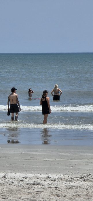The family wades out together, boogie boards ready for the next set.