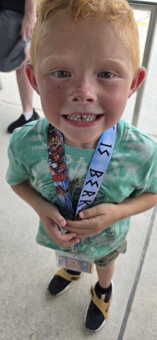 A gap-toothed grin over a fistful of park lanyards, proof of a great day so far.