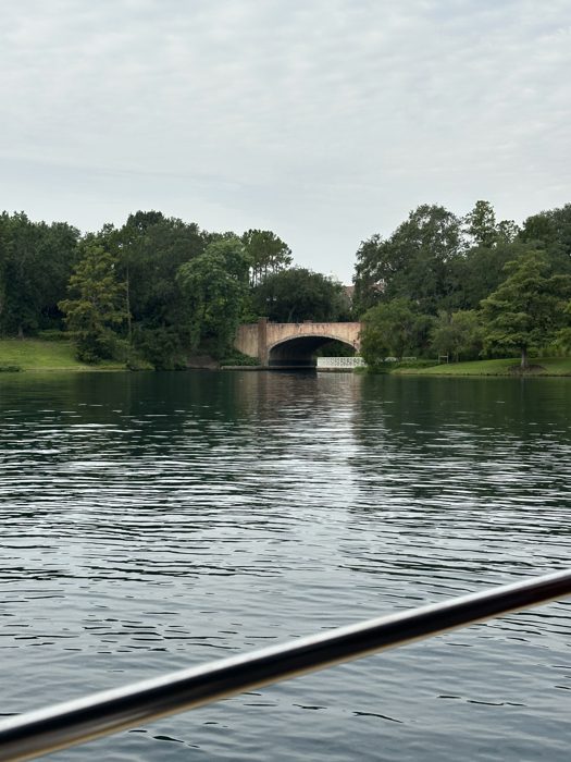 A stone footbridge arches over the resort's calm canal as the water taxi glides toward it.