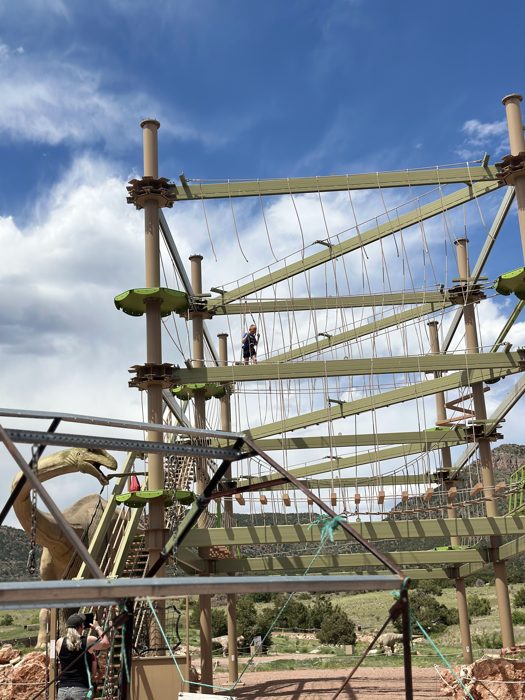 Climbing high on the aerial ropes course against a big Colorado sky.