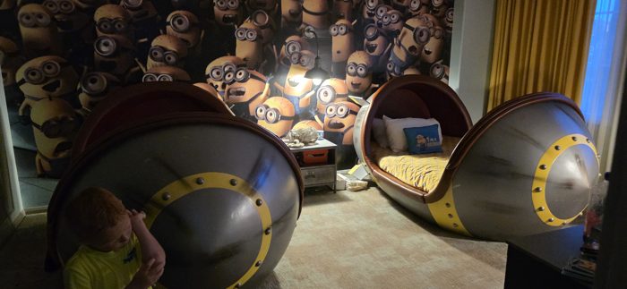 A pair of pod-shaped Minion beds tucked into the kids' room, wallpapered floor to ceiling with grinning Minions.