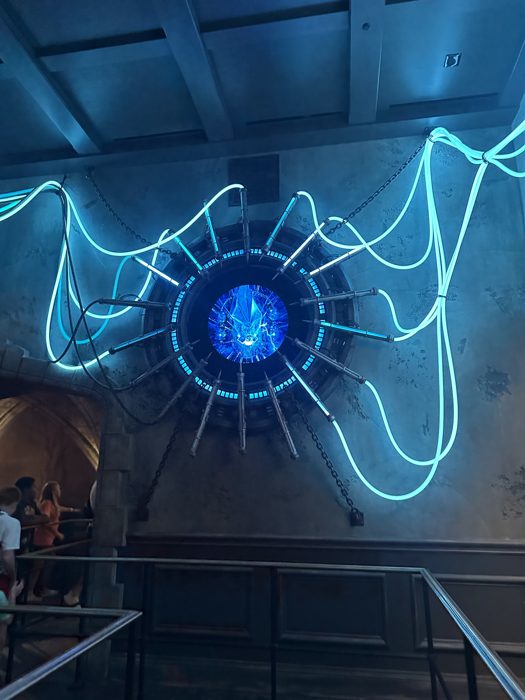 A crackling blue energy device glows overhead as we wind through the queue line.