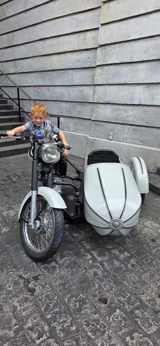 Grinning ear to ear astride the sidecar bike, ready to zoom off.