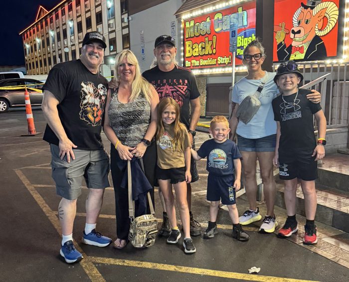 The whole family posing together outside under the neon glow on the Strip.