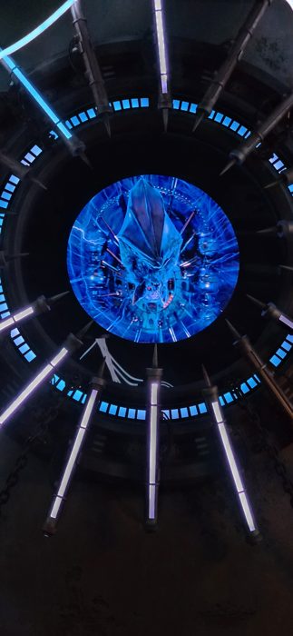 Looking straight up at a glowing blue monster face from inside the ride vehicle.