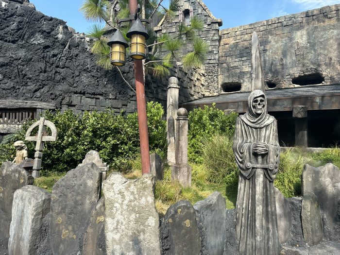 A grim stone reaper stands watch over the fog-shrouded graveyard set.