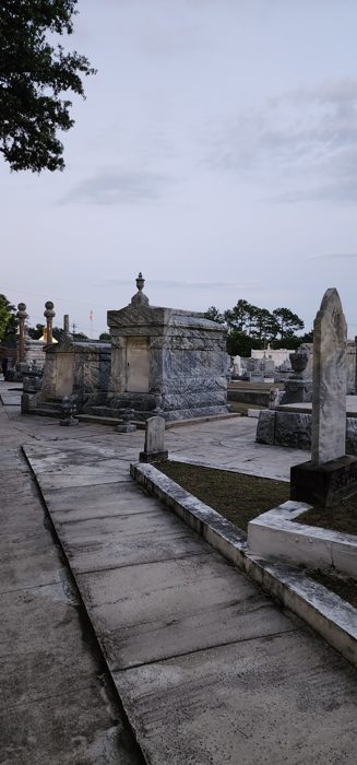 A long shadowed alley of marble tombs receding into the distance.