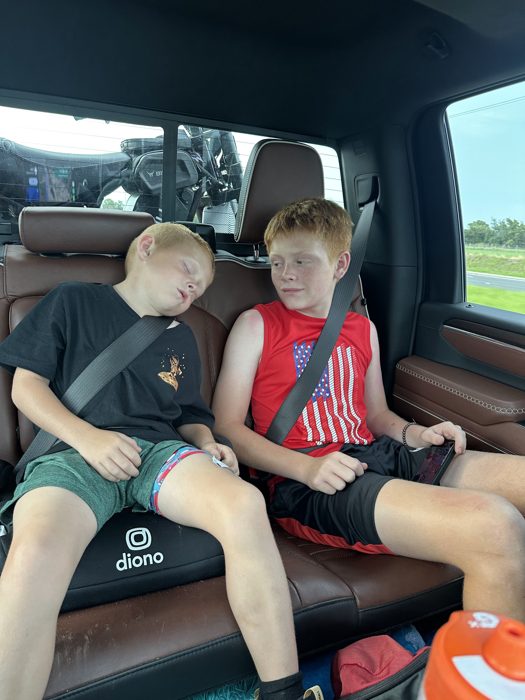 Wiped out from a full day, one of the kids catches a nap on the ride while the other zones out beside him.