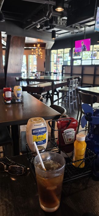 A cold drink and a full condiment caddy waiting at our table before the food arrives.