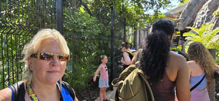 Waiting in the jungle-fenced queue line with the family, rocky formations rising up ahead.