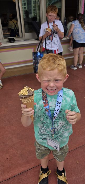 One of the kids scrunches up a face over a chocolate ice cream cone loaded with gold sprinkles.