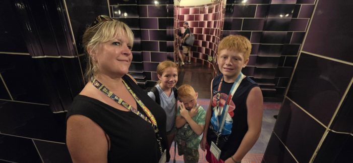 The family pauses together in a moody, tiled corridor between attractions.