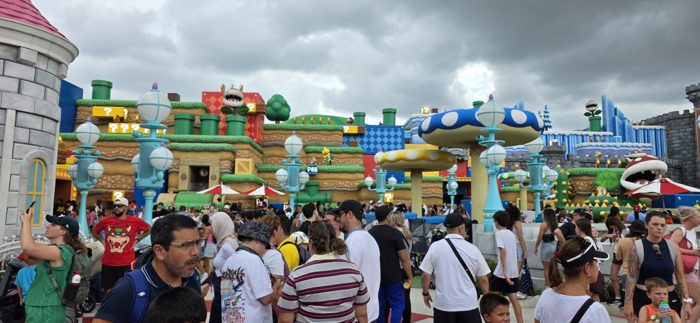 Storm clouds roll in over the pipes, blocks, and castle towers of the theme park land.