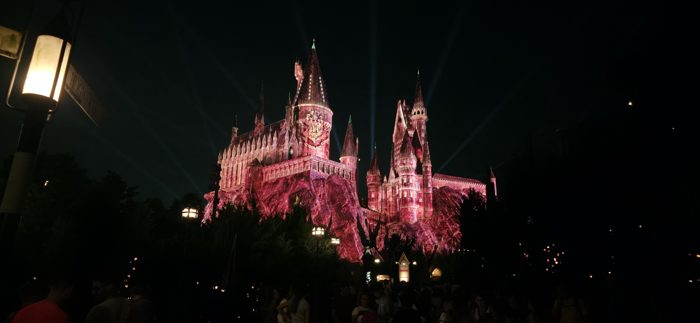Hogwarts castle glows deep crimson under a dazzling nighttime light show at Universal.
