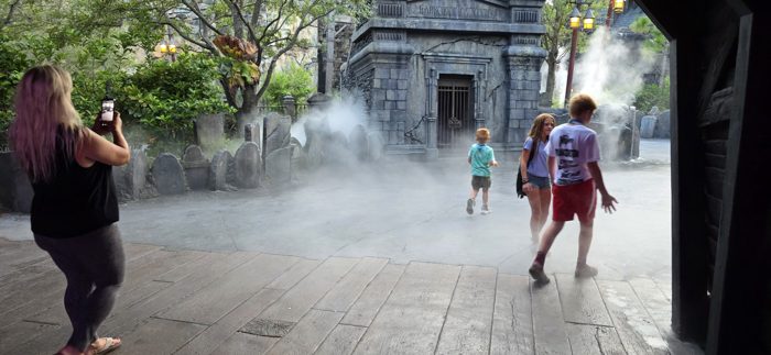 The kids run together through the swirling fog while a parent captures the moment on her phone.