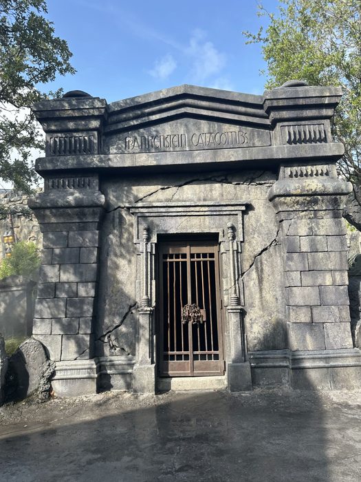 The cracked stone facade and locked iron gate of the Frankenstein Catacombs entrance, quiet in the morning light.