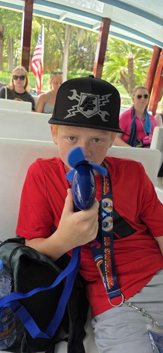 One of the kids holds a mini fan up close, cooling off on the boat ride in the Florida heat.