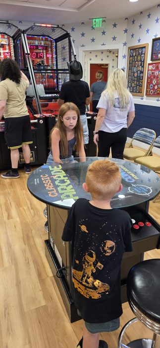 Another round at the arcade table while the grown-ups wander the game room behind them.
