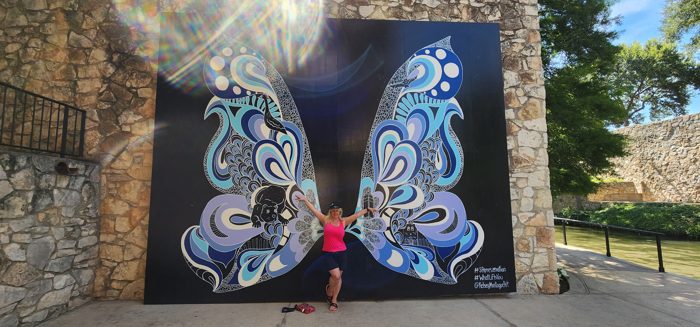 One of the kids dwarfed by San Antonio's giant blue butterfly mural.