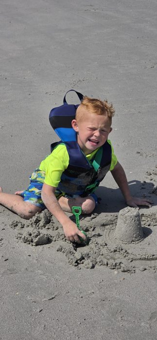A gleeful squint from one of the kids mid-sandcastle-construction, green shovel in hand.