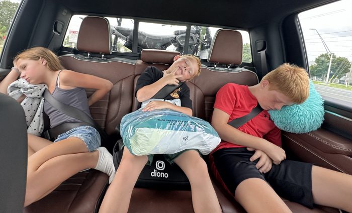 Three of the kids sprawled out and dozing in the backseat with the gear loaded up behind us.